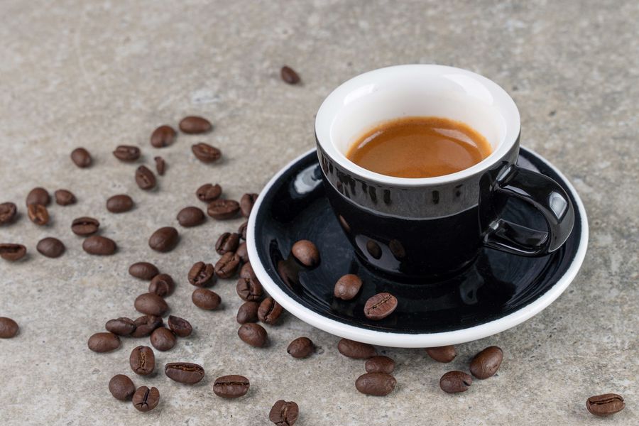 Coffee beans scattered around a cup of coffee