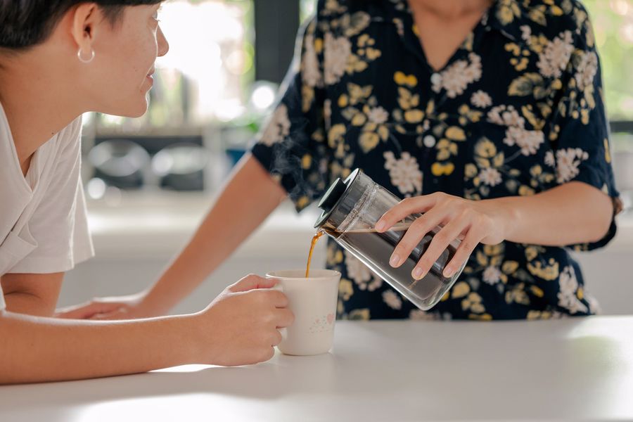 Person pouring coffee for her friend