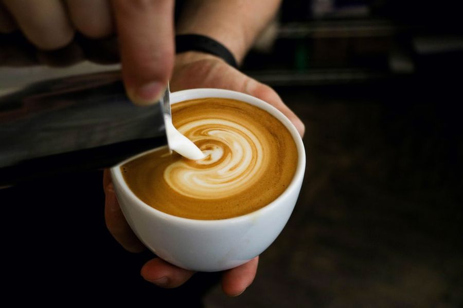 Milk being poured on a cup of coffee