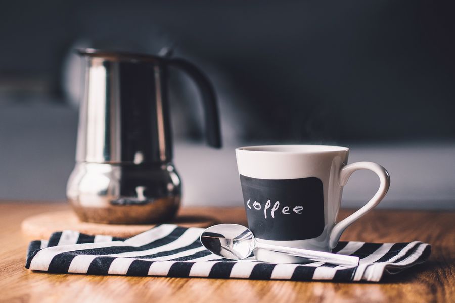 Kettle beside a cup of coffee