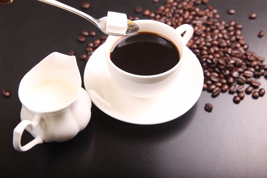 Sugar cube being added to a dark coffee