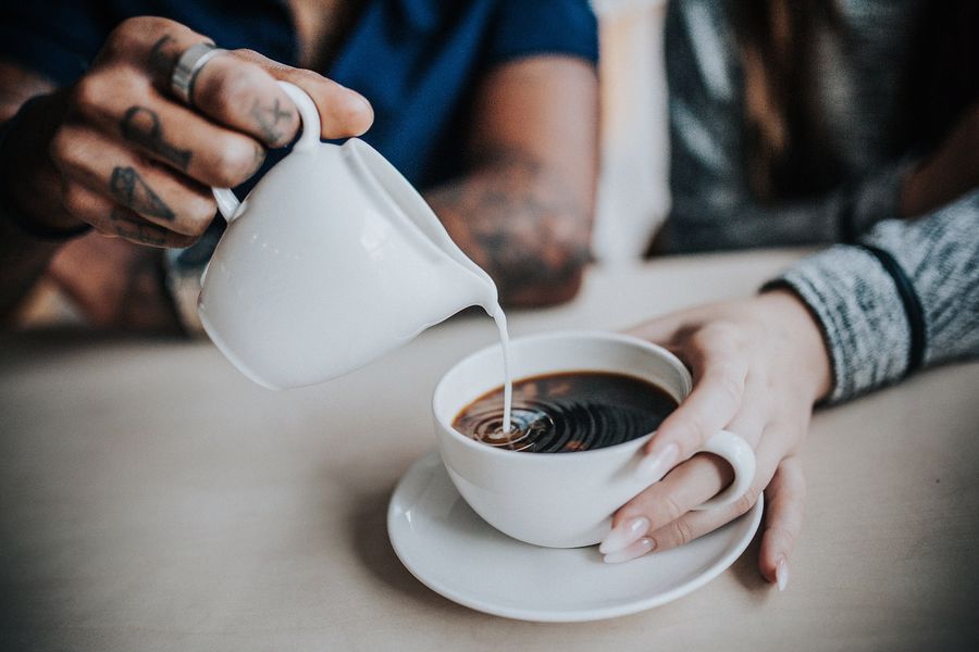 Man adding milk to a woman's cup of coffee