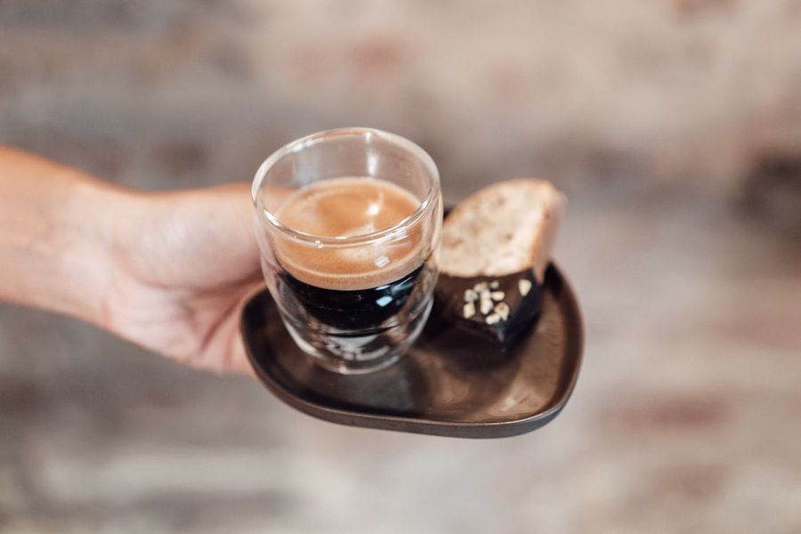 Person holding a cup of coffee with a biscotti