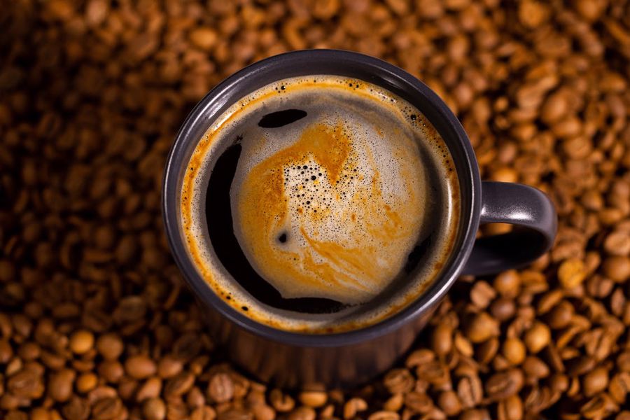 Cup of coffee on top of coffee beans