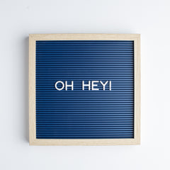 Navy letter board with white letters that read oh hey!