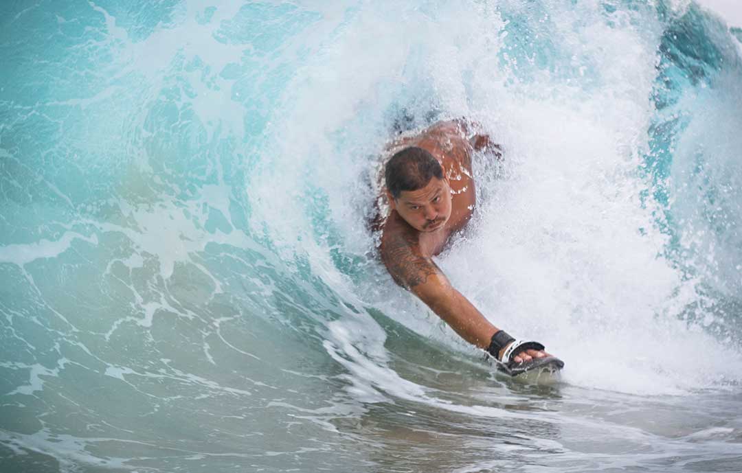 8 Essential Writing Tips When Starting Your Surf Blog man riding wave in hawaii on bodyfuring handboard