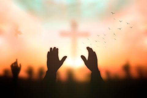 hands raised with the silhouette of the cross