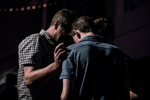 men touching forehead while praying for the nations