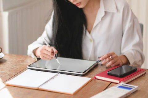 woman writing on ipad