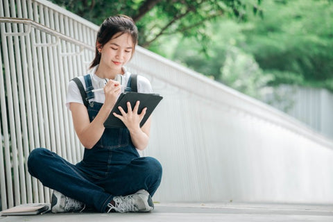 young woman writing on ipad