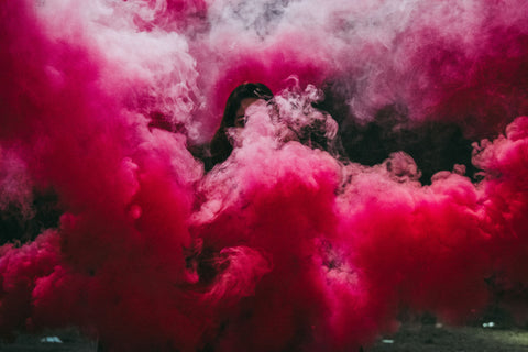 Girl sitting in the middle of a large pink cloud of smoke