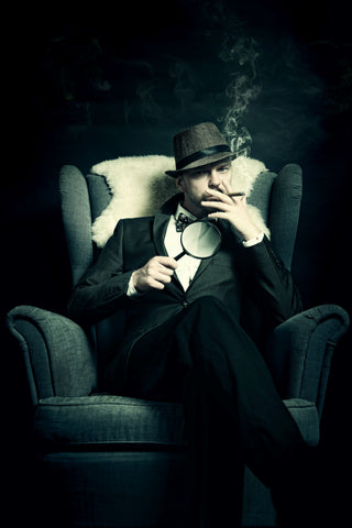 Man sitting in a chair with a magnifying glass and a cigar