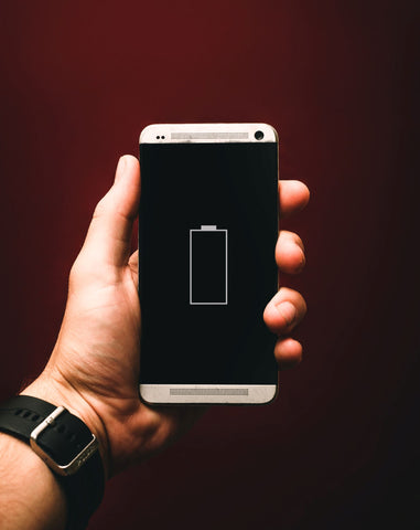 Man holding an iphone with his left hand with a dead battery on the phone's screen