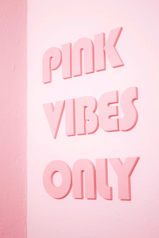 The words Pink Vibes Only on a pink background which looks like a cement wall painted pink