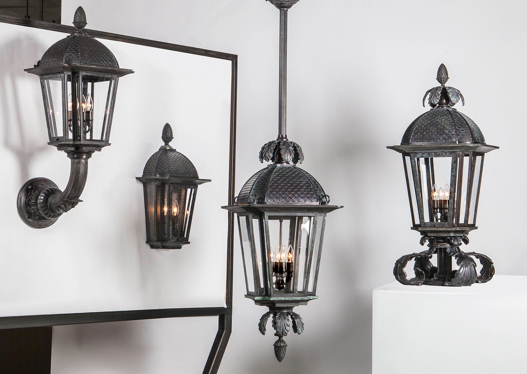 A studio image of the cast bronze lantern family - the wall lantern, wall sconce, ceiling lantern and pier light.