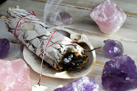 Sage burning surrounded by amethyst and rose quartz