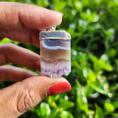 Amethyst Slice Pendant held in front of a shrub