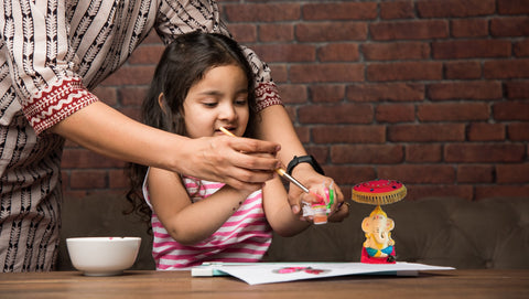 Little kid doing a craft with her mom's hands helping her.