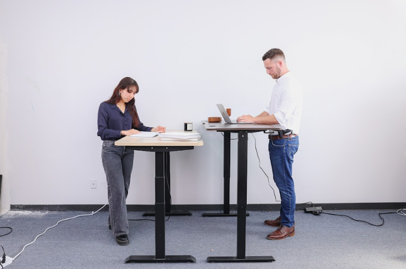 man and woman using a standing desk