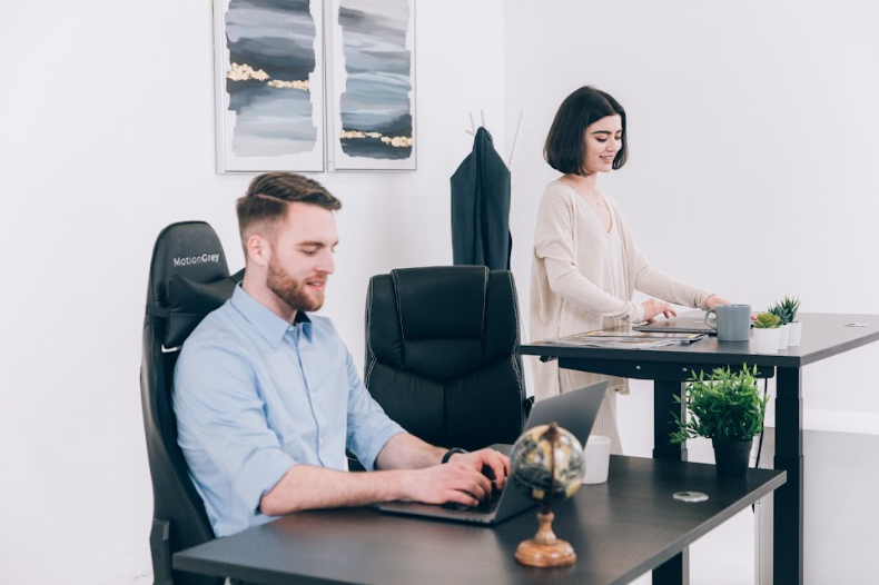 man and woman working on standing desks