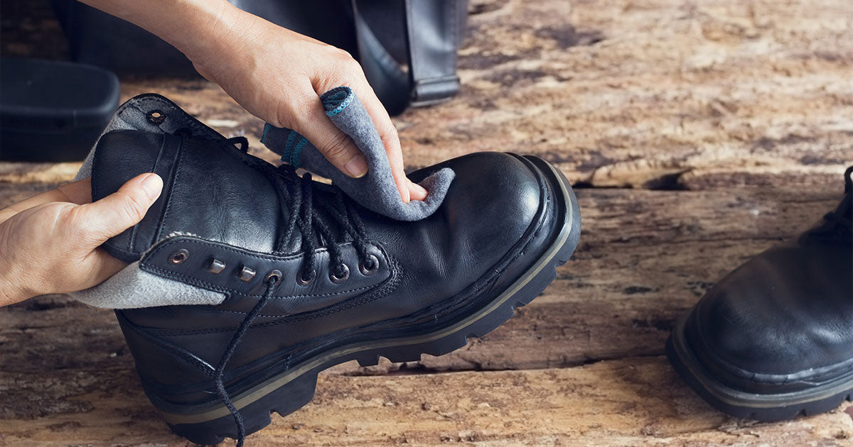 Cleaning black boots on wooden background