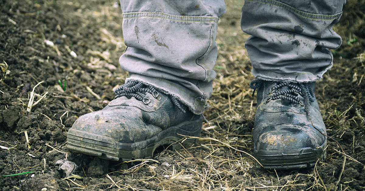 Man wearing dirty work boots on grass