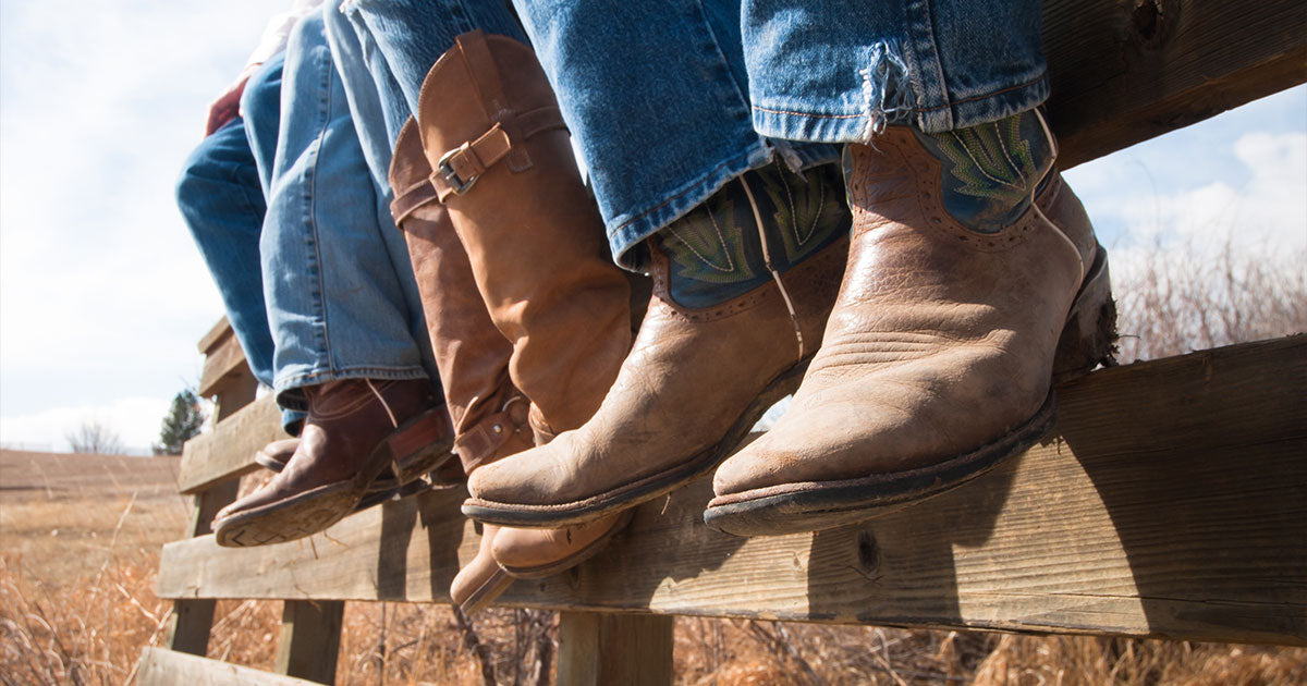 People sitting on fence with cowboy boots