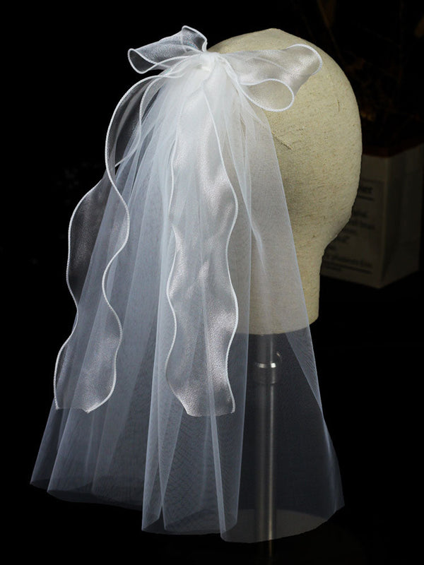 https://cdn.shopify.com/s/files/1/0252/9823/9585/files/ivory-one-tier-bows-tulle-cut-edge-drop-wedding-veils-wedding-veils-2_600x.jpg?v=1701982821