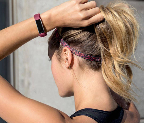 Blonde woman with a pink Fitbit on her arm.