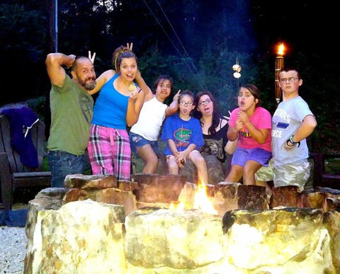 Seven people acting silly by a campfire.