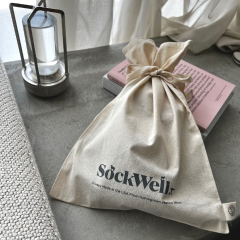 Sockwellのロゴ入りギフトバッグの商品紹介をしている