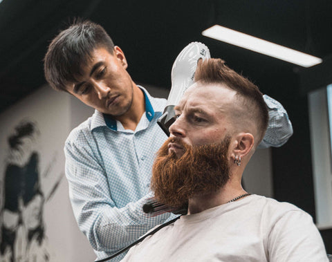 Man with red beard having his beard trimmed