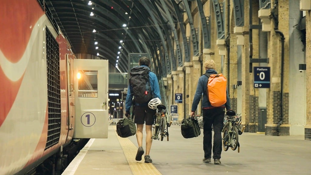 Al and Tem are walking down a train station platform with their bikes in hand