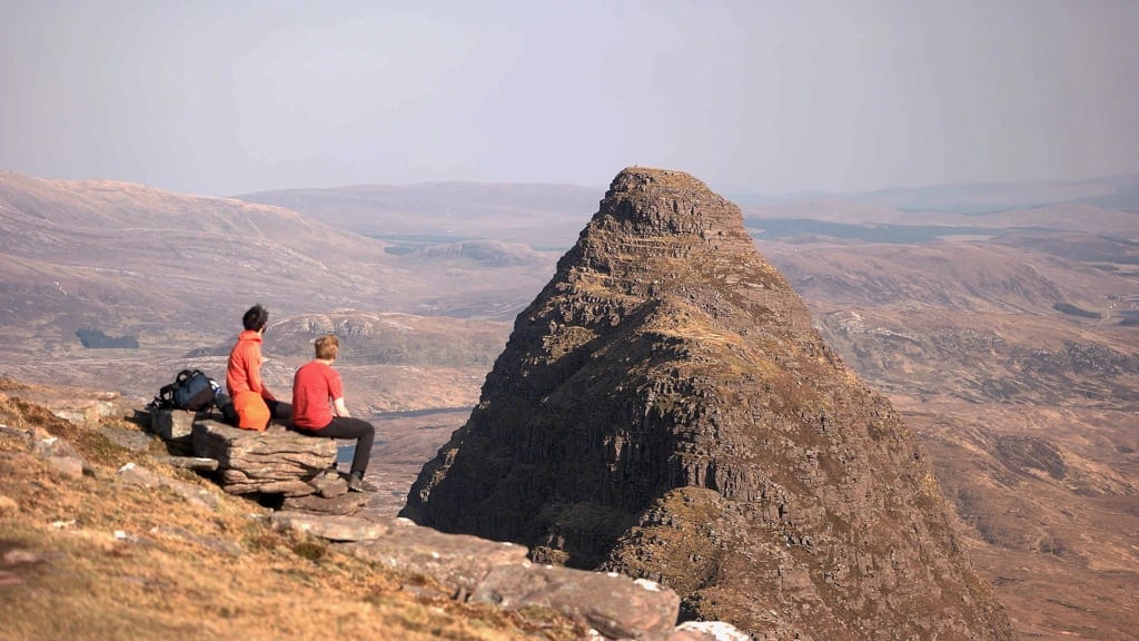 Al and Tem sitting on a rock, high up, looking out to the vast landscape of scotland