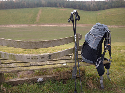 Rucksack and trekking poles leaning against a bench