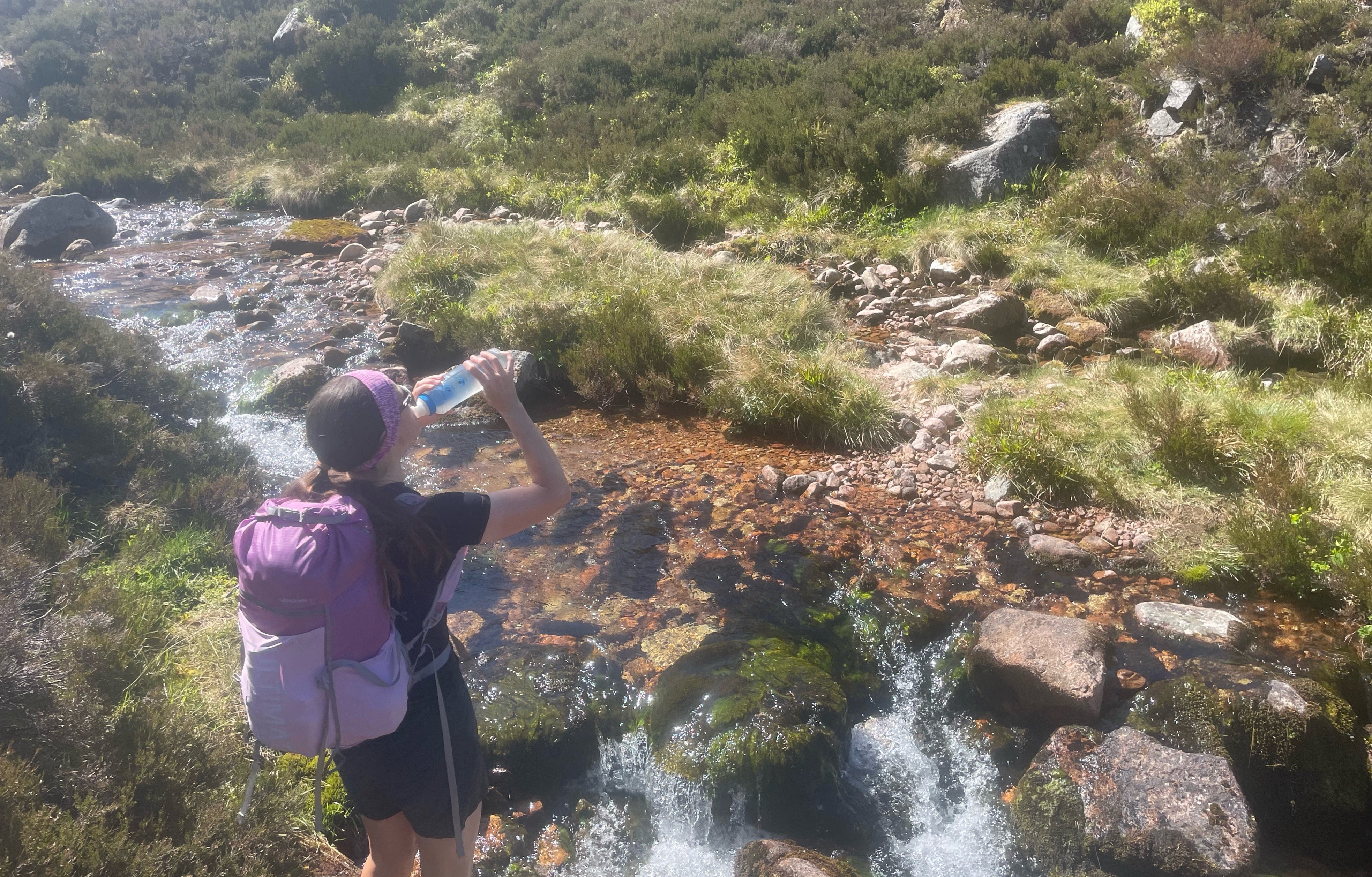Katie palmer drinking water from a mountain stream. Its crystal clear