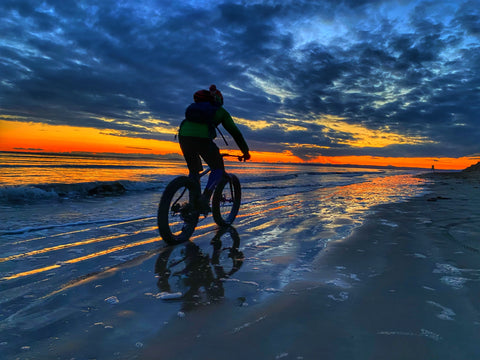 Cycling a fat bike along the beach against a dramatic sunset