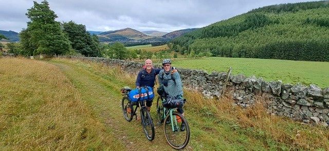 two friends bikepacking with grassy backdrop