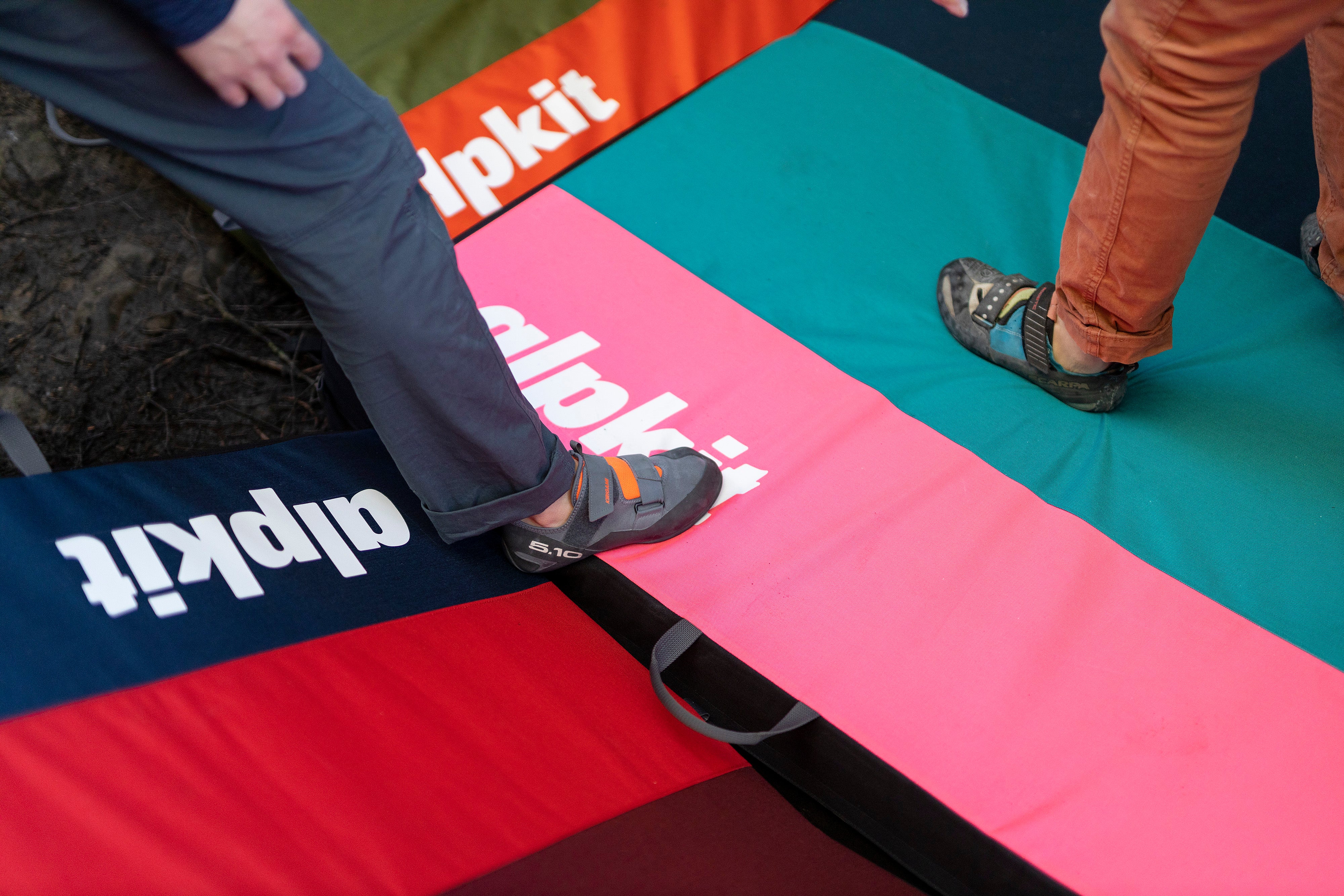 Two climbers standing on colourful Alpkit UK made bouldering mats