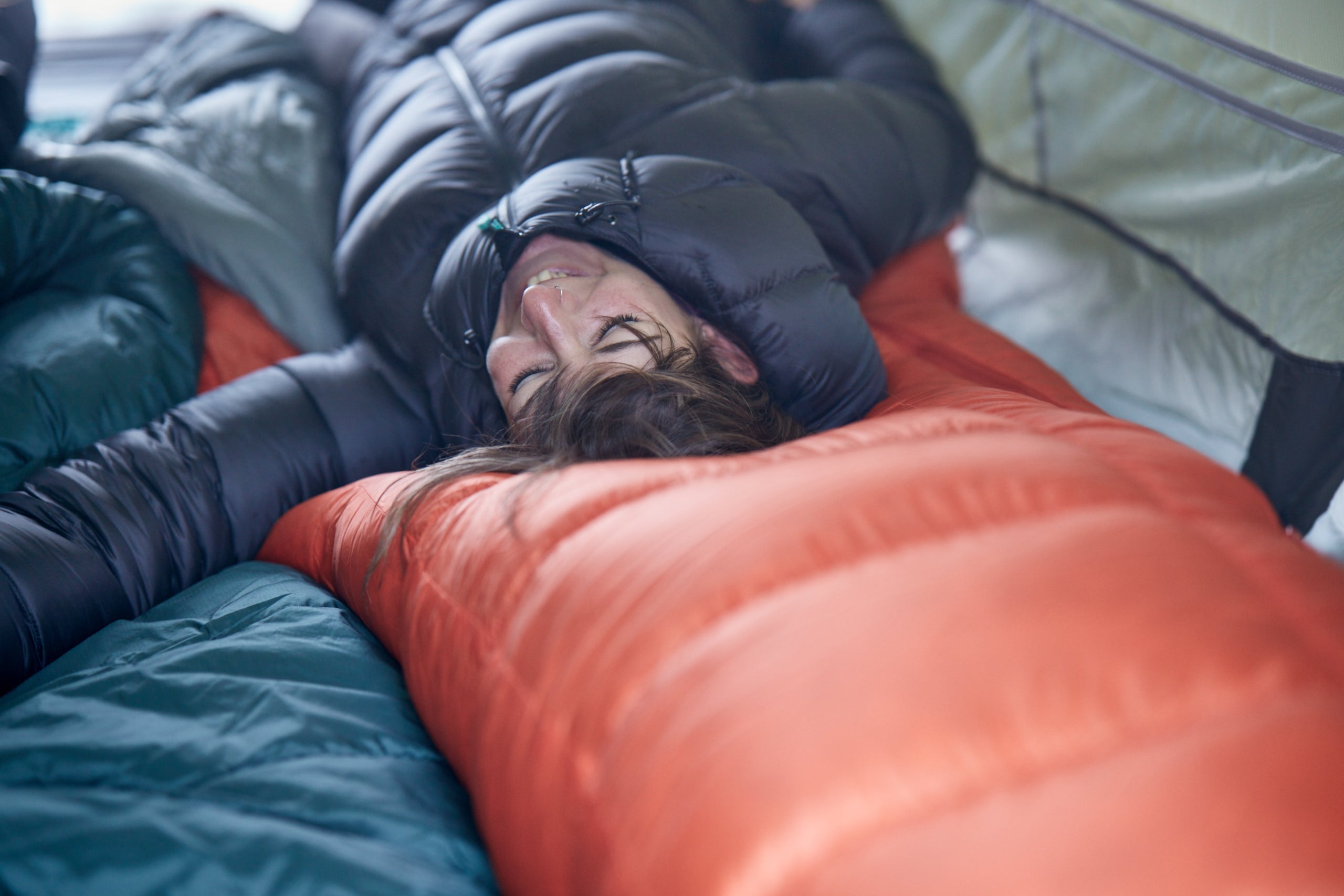 woman lying in tent on sleeping bag in a down jacket