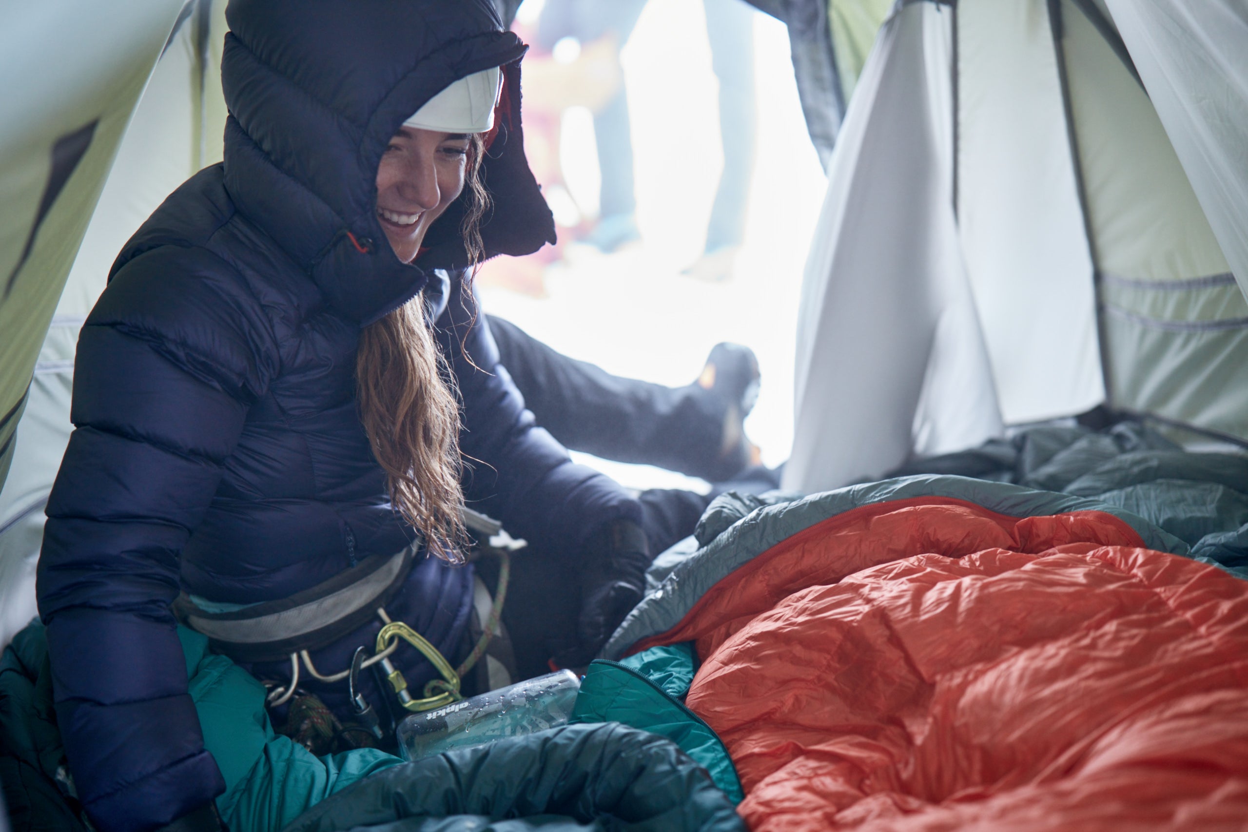 Woman in down jacket in tent with sleeping bag