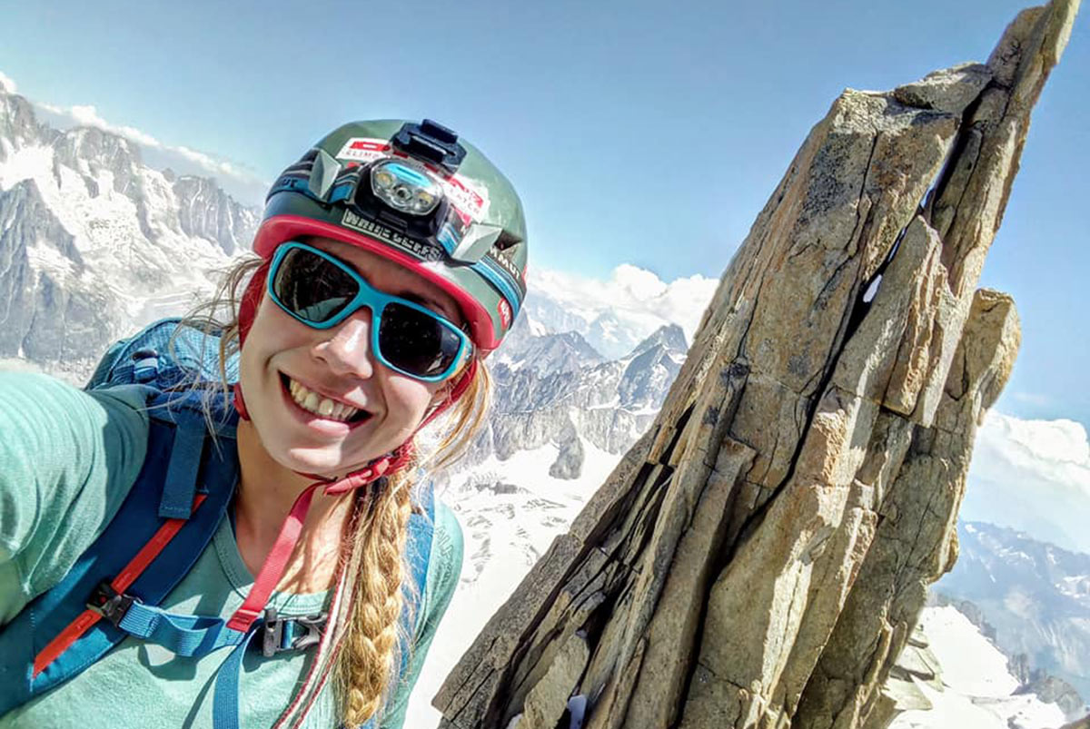 Female climber at the top of a sharp alpine ridge