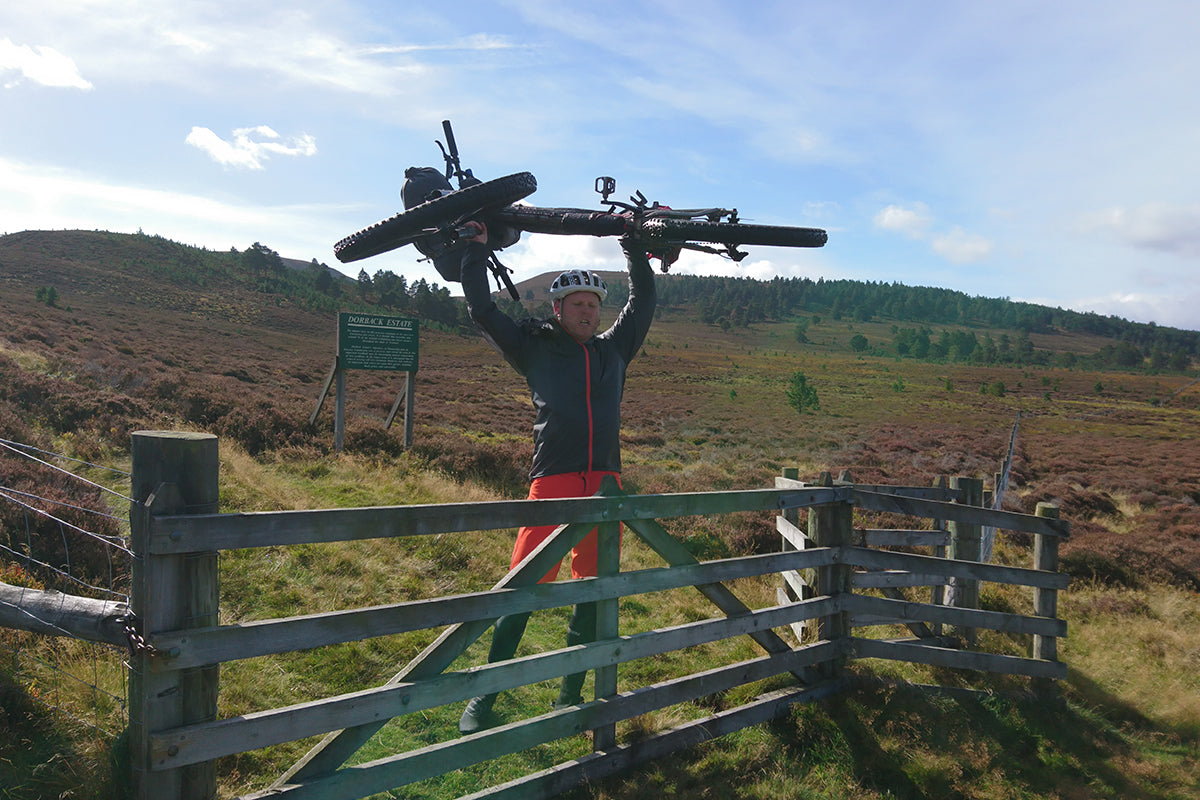 Bikepacker lifts bike over gate