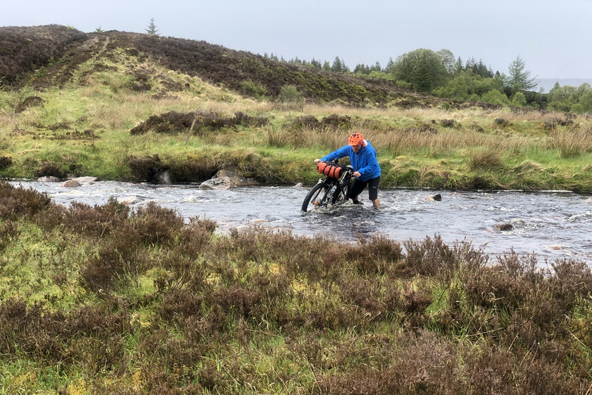 Crossing a deep stream while bikepacking in Wales