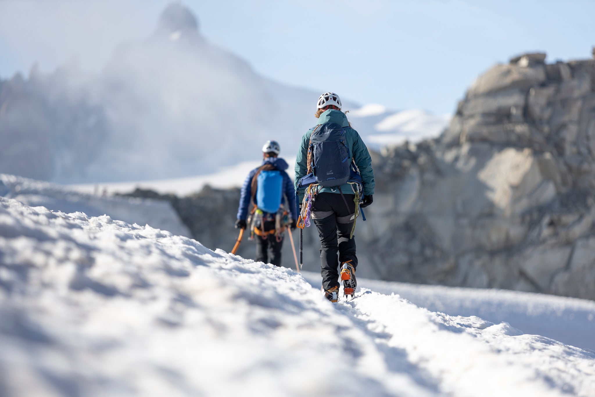 Walking into the distance in the snowy French Alps with crampons on and a 0Hiro Primaloft insulated jacket