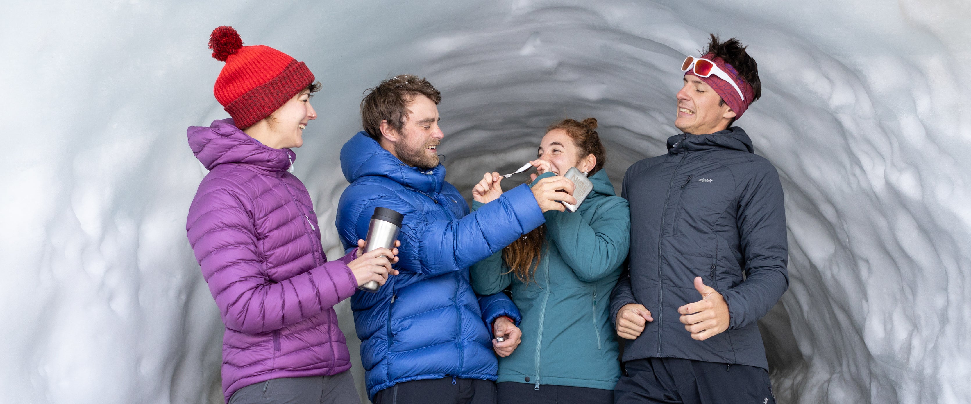 Four people wearing down jackets and Primaloft synthetic insulated jackets in an ice cave in Chamonix