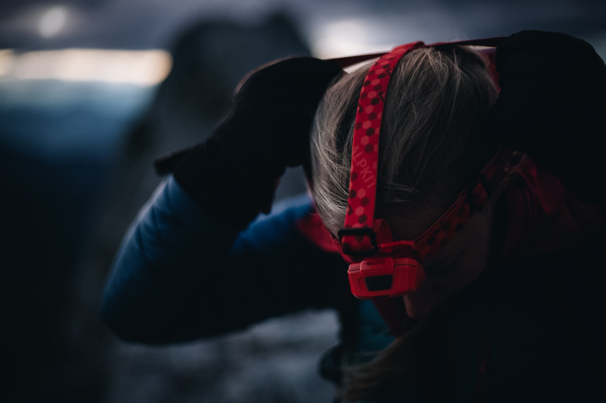 three people walking down a mountain in the pitch black with head torches on