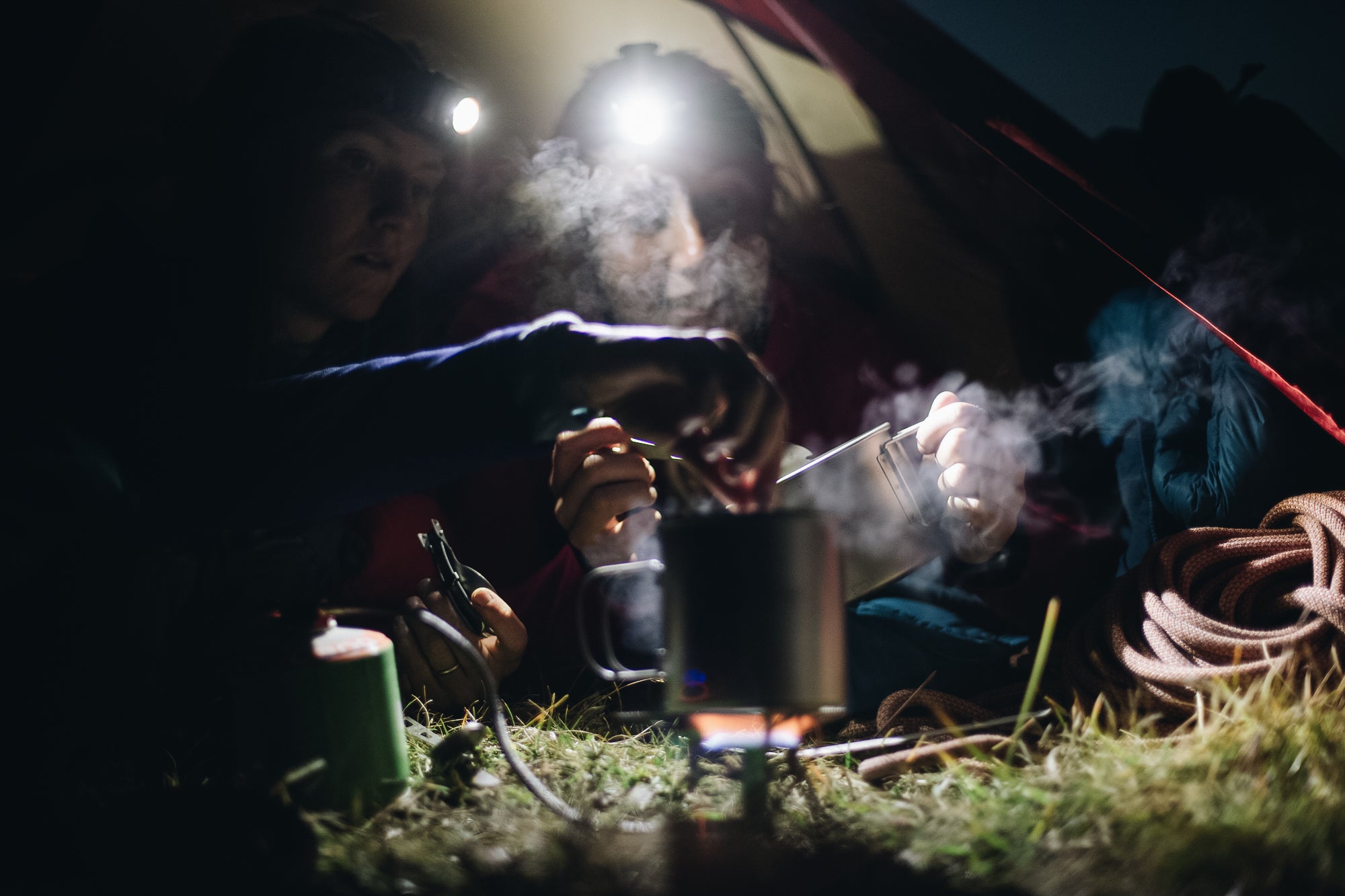 Two women camping and cooking by head torch light in the Slovenian mountains
