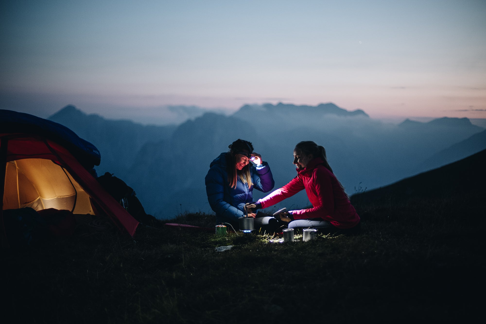 two women wild camping in the Slovenian mountains and cooking by head torch