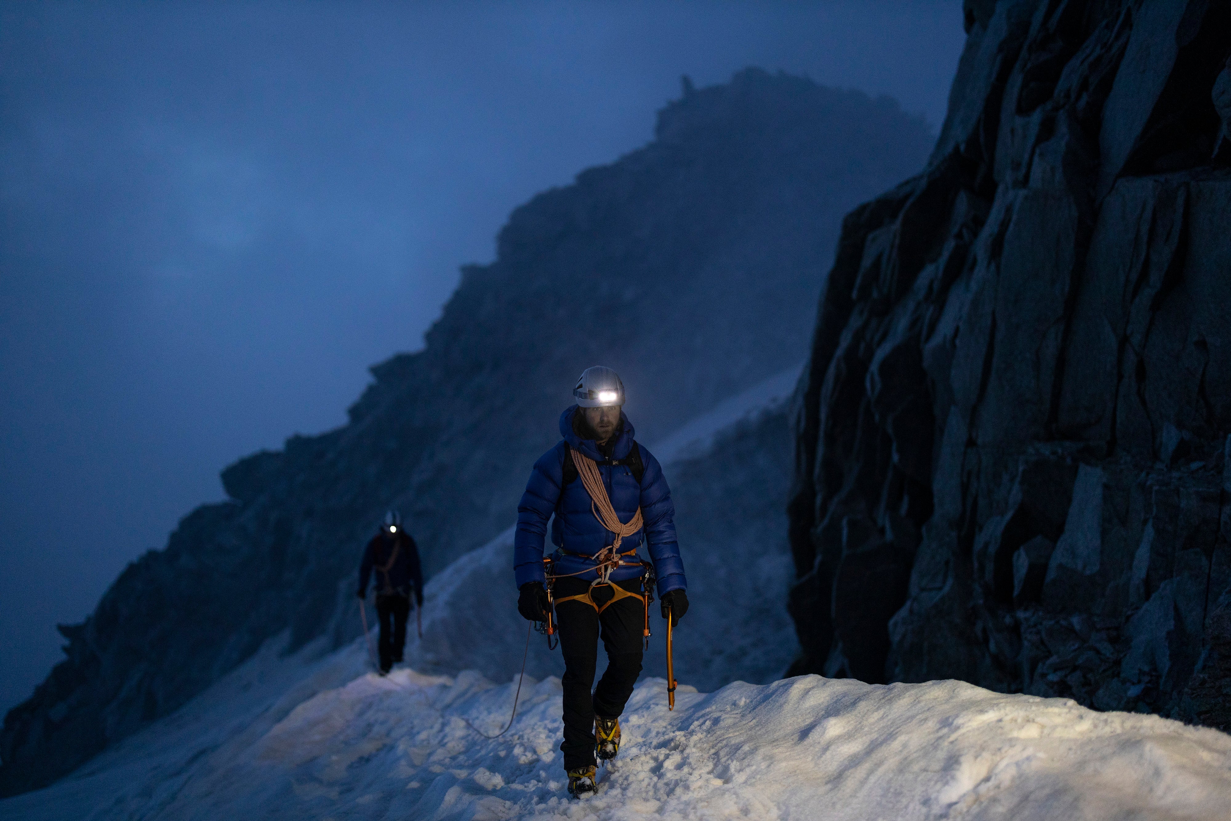 Two men crossing a snowy ridge by headtorch in the French Alps